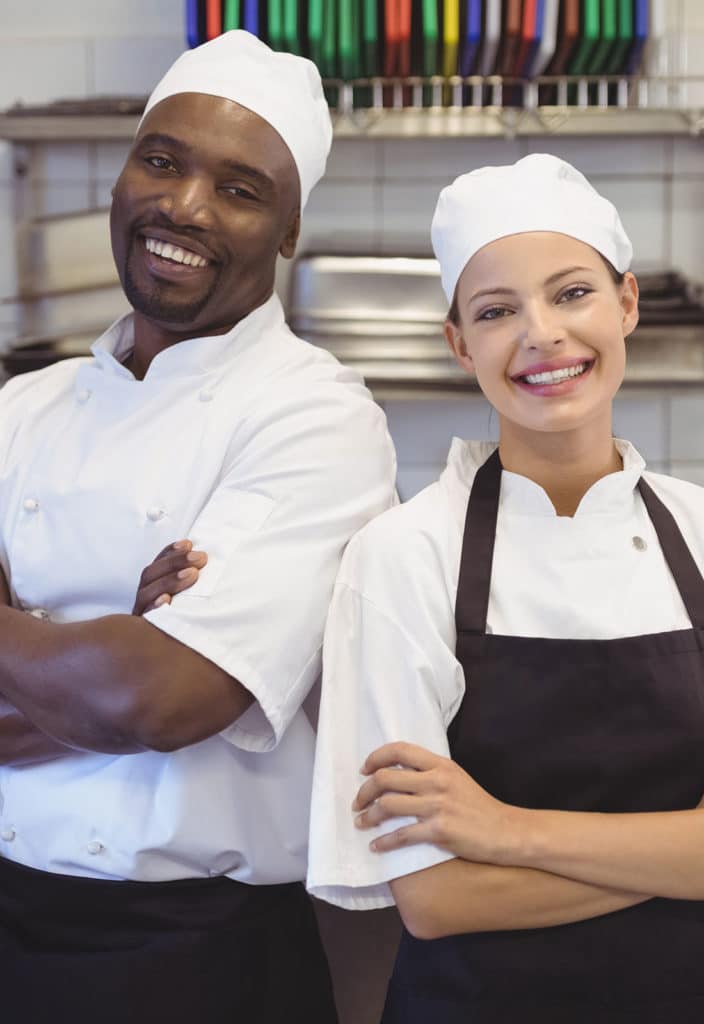 Two chefs standing with arms crossed in the commercial kitchen