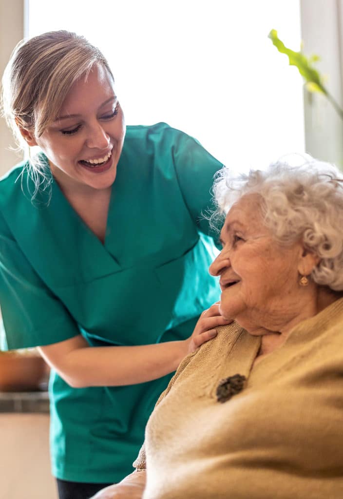 Friendly nurse supporting an elderly lady