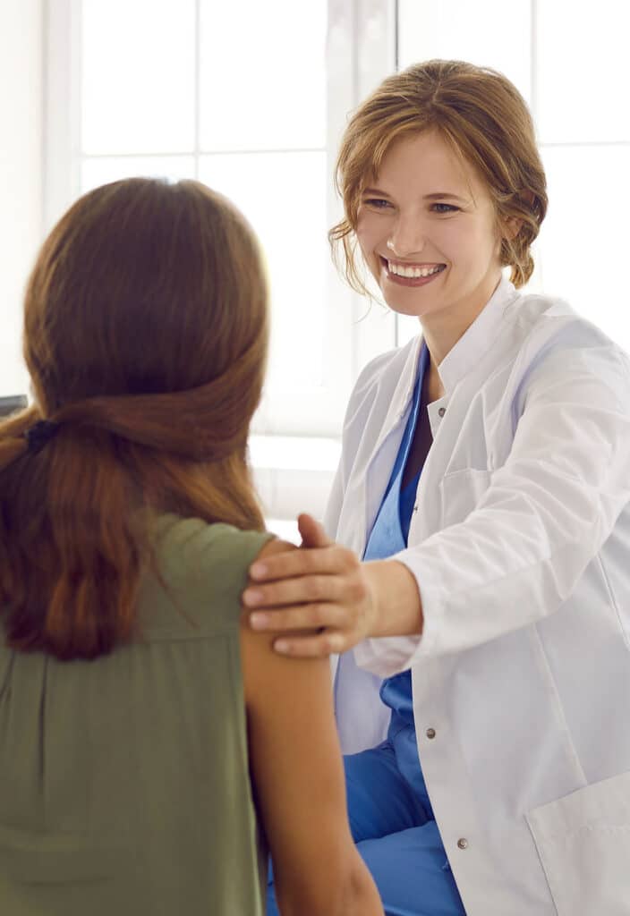 Nurse in a white coat supporting a teenage child.